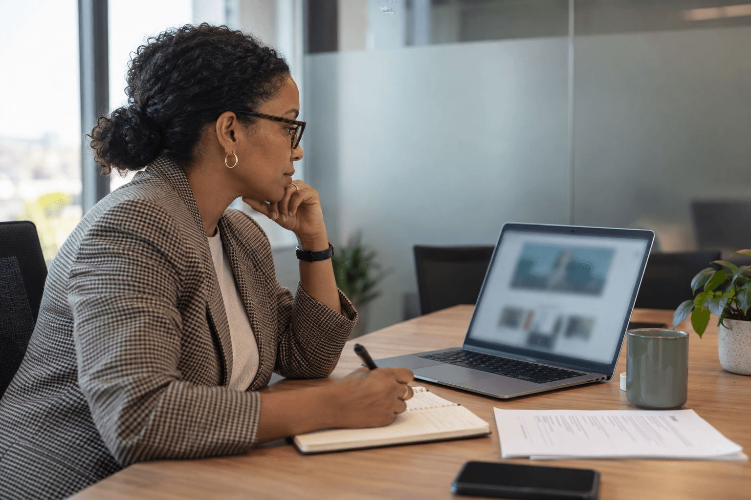 A recruiter taking notes while reviewing a candidate profile on a laptop
